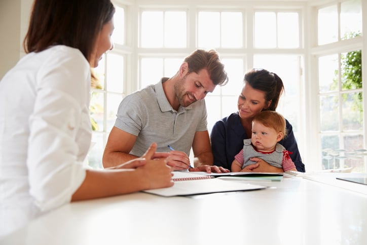 couple with baby signing house closing documents